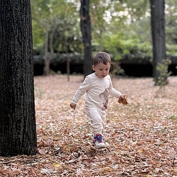 Fotografie surprinsă în septembrie, în parc, cu Teo alergând printre frunze