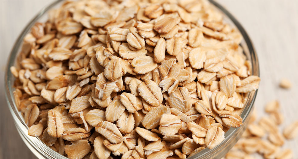 A transparent bowl filled with oat flakes.