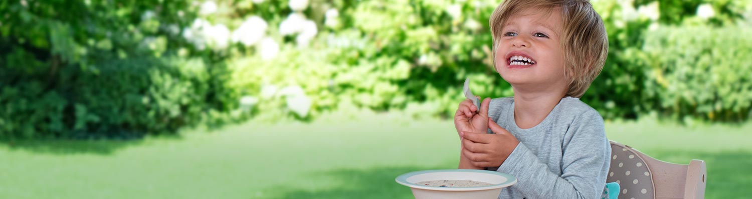 A child is eating from a bowl outdoors.