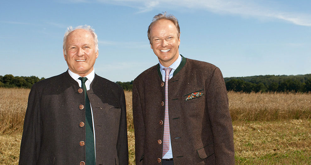 Two men in suits stand in a field.