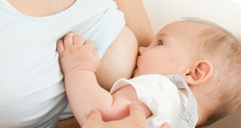 A baby is nursing from a woman.