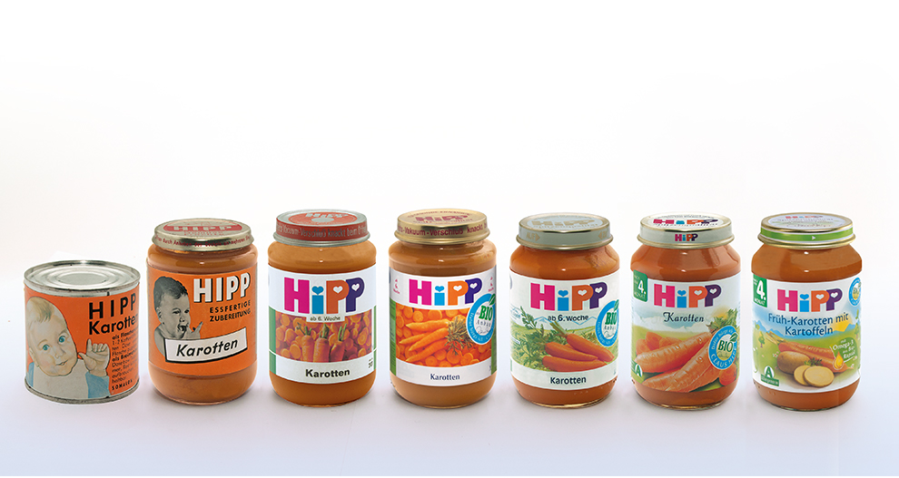 O colecție de șapte borcane și o cutie de mâncare pentru copii, toate etichetate cu marca "HIPP" și având morcovul ca ingredient principal.